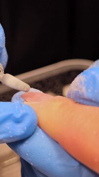 Vertical close-up video of gel polish removal with electric nail drill. Professional manicure procedure in salon. Hardware manicure process, cleaning of nails by milling cutter. Close up female hands