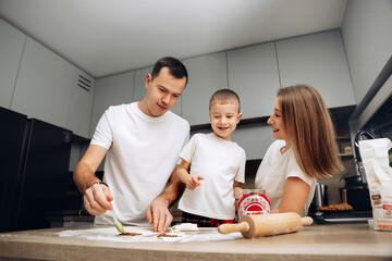 Family enjoys baking cookies together in modern kitchen during afternoon activity with joyful smiles and laughter as they create sweet treats