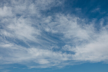 Obraz premium Clouds drift slowly across a bright blue sky in midday