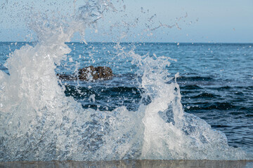 Fototapeta premium Water splashes from waves hitting rocks by the shoreline