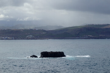 Gran Canaria, view towards the main body of the island from El Confital beach on the edge of Las Palmas de Gran Canaria, rain sweeping through the island
