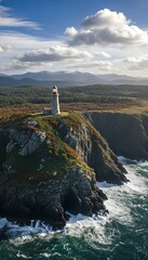 Majestic stone lighthouse stands proudly on a rugged cliff overlooking the powerful ocean waves and distant snow-capped mountains under a dramatic sky.