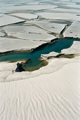 White sand dunes and blue water channels create a stunning natural landscape with intricate patterns and vibrant contrasts under a clear sky.