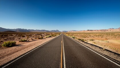 a long straight road disappears into the horizon surrounded by rugged desert landscapes under a clear blue sky