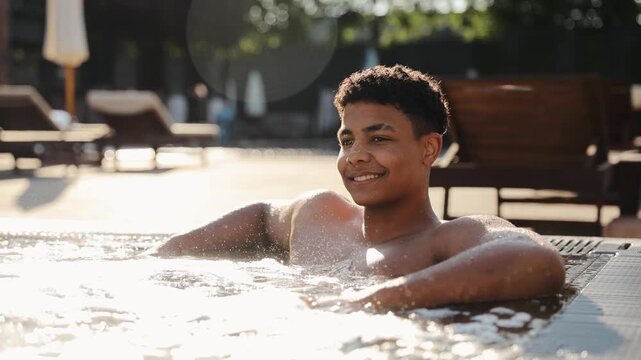 Young black man swimming in hot tub, relaxing in warm water with bubbles, enjoying hydrotherapy and vacation