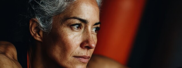 Close up of a woman with gray hair looking thoughtful during a workout session in a gym environment in the late afternoon