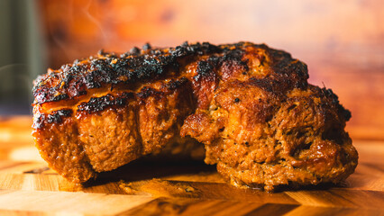 Whole pork joint freshly out of the oven, crispy fat, steaming hot on a wooden board. Juicy inside,...