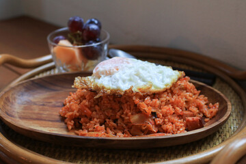 Kimchi fried rice with egg on wooden plate in cozy restaurant, Korean food.
