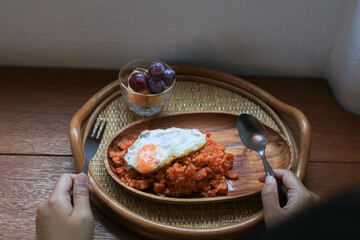 Kimchi fried rice with egg on wooden plate in cozy restaurant, Korean food.

