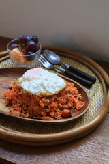 Kimchi fried rice with egg on wooden plate in cozy restaurant, Korean food.
