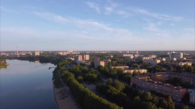 Drone flies along the Volga River at sunrise in Tver. The calm water reflects the soft morning sky, and the city is visible on both sides of the river.