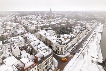 Dutch tower town Zutphen in the Netherlands covered in snow on river IJssel seen from above. Aerial winter wonderland during a snow storm
