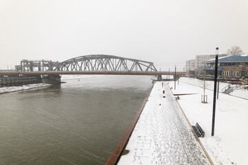 Bridge and quay of Dutch tower town Zutphen in the Netherlands covered in snow on river IJssel seen from above. Aerial winter wonderland during snow storm