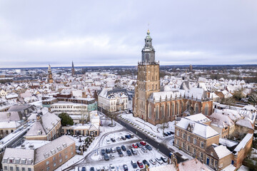 Fototapeta premium Medieval Hanseatic Dutch tower town Zutphen in the Netherlands covered in snow with historic heritage buildings and river IJssel passing by in the background behind Walburgiskerk church tower