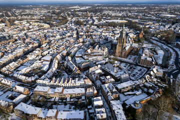Obraz premium Medieval Hanseatic Dutch tower town Zutphen in the Netherlands covered in snow with historic heritage buildings and river IJssel passing by in the background behind Walburgiskerk church tower