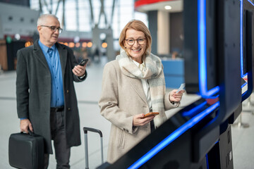 Senior woman using self check-in kiosk at airport