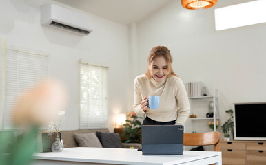 Happy young Asian woman using tablet and smartphone in a stylish cafe, drinking coffee and working...