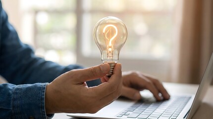 Creative innovation and business idea concept with professional holding glowing light bulb while working on laptop in modern workspace environment
