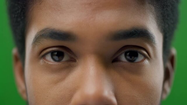 Extreme close-up of a young man's face with green background.
