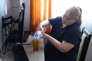 Woman pouring water into glass during home office work