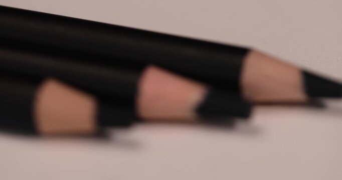 a row of black wooden pencils folded on cheap loose paper, wooden pencils with graphite lead for drawing or other work