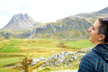 A laughing tourist against the backdrop of the mountainous landscape of Lukavica in Montenegro. Represents joy of exploration, positive outdoor experience, and optimistic travel storytelling concept.