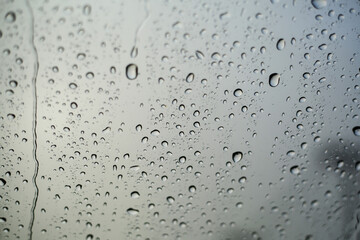 Raindrops on the windshield during the rainy season. A landscape of raindrops on the gray glass.