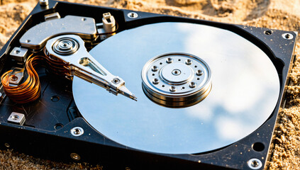 Open Hard Drive Mechanism on Sandy Ground