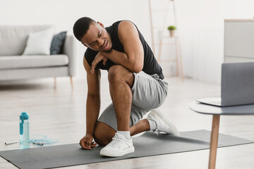 Obraz premium Fitness Burnout. Exhausted African American Guy Tired Of Online Workout Exercising At Laptop Sitting On Floor At Home. Beginner Resting After Difficult Exercise Concept. Selective Focus