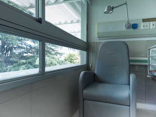 Empty chair in a bright hospital patient room