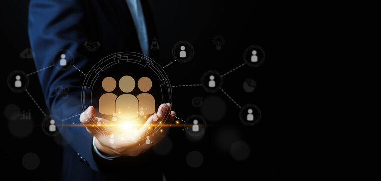 Human resources and business network concept with businessman holding glowing team icon and connected user symbols, representing talent management, teamwork, collaboration, leadership. - Powered by Adobe