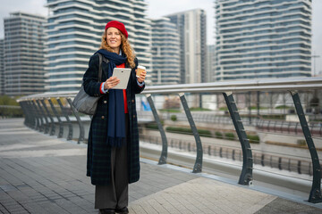 Woman holding tablet and coffee cup in city