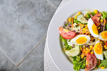 Top view of egg salad on the white plate. cruttong. mix salad. boiled egg. dressing. vegetables. high angle, above, flat lay. close up. granite table on the background. isolated. half. copy space.