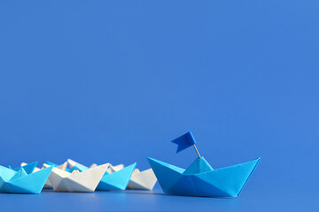 One origami boat with flag and other ones on blue background