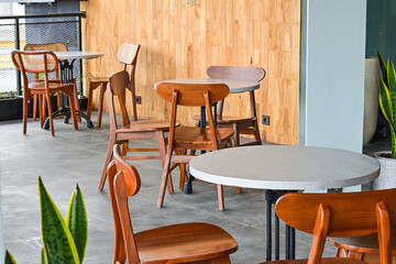 Empty tables And wooden chairs, grey or gray tables and chairs set. outdoor seating for restaurant, Cafe or coffee shop. Plants, leaves, green, nature, wall. wood. granite. brown. white. wall. decor, 