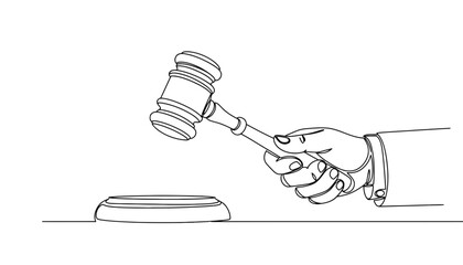 A hand holding a gavel in a courtroom setting with a judge's bench