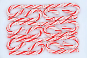 Above top view of candy canes arranged in a pattern on a square porcelain plate.