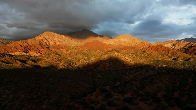 Wide of sunlit Fiambala mountain range under dramatic clouds in remote high desert region