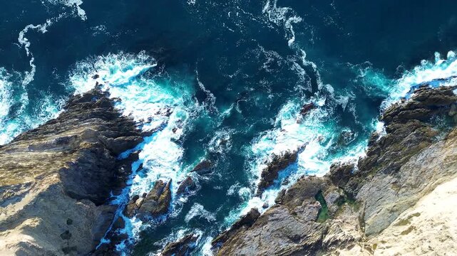 Drone aerial landscape of deep ocean swell and coastal waves crashing along rocky headland coastline with cove inlet and cliff face at Malua Bay Australia travel tourism holidays fishing nature