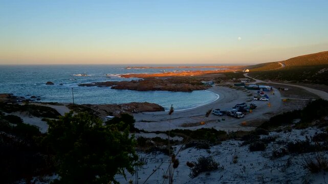 Dawn view from Tietiesbaai dune of early morning moonset over seaside campsite