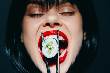 Bold woman savoring sushi with vibrant red lips, showcasing a tantalizing food experience in a dramatic close-up shot.