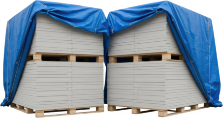 Two stacks of gray rectangular panels resting on wooden pallets partially covered by a bright blue tarp tied with cord for protection covering construction material building outdoor