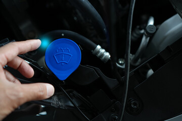 windshield washer fluid in a car, highlighting the washer reservoir, blue cap, and essential...