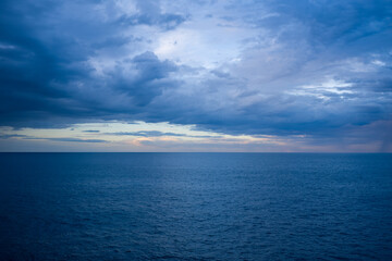 Vast expanse of the Adriatic Sea stretches to the horizon beneath a sky filled with layered, moody clouds at dusk. The scene captures subtle color gradients and gentle waves, evoking a tranquil and