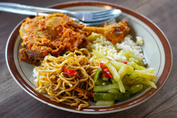 Bebek rica spicy duck dish with rich chili seasoning, served with steamed rice, stir-fried noodles, and vegetables, bold Indonesian flavor with rustic homestyle presentation