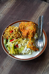 Bebek rica spicy duck dish with rich chili seasoning, served with steamed rice, stir-fried noodles, and vegetables, bold Indonesian flavor with rustic homestyle presentation