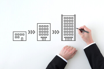 会社を大きく発展させるイメージを描くビジネスマンの手