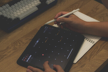 Top view of person using stylus pen on tablet with digital calendar for 2026 planning on wooden desk, home office workspace concept.