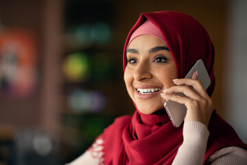 Closeup portrait of pretty millennial muslim lady in hijab talking on cellphone with lover or...
