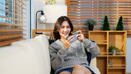 Asian young beautiful woman playing mobile game on smartphone at home.